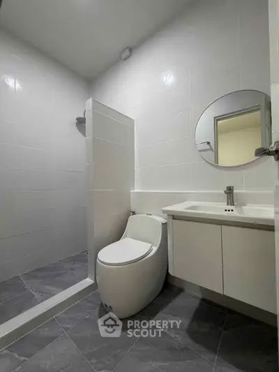 Modern bathroom with sleek design, featuring a round mirror and contemporary fixtures.