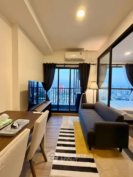 Modern living room with city view, stylish furniture, and large windows for natural light.