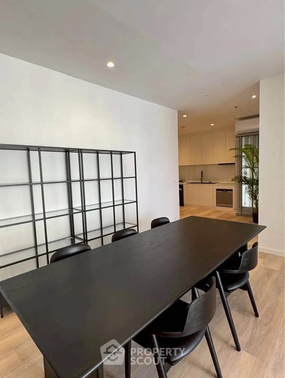 Modern dining area with sleek black table and chairs, open kitchen layout, and minimalist design.