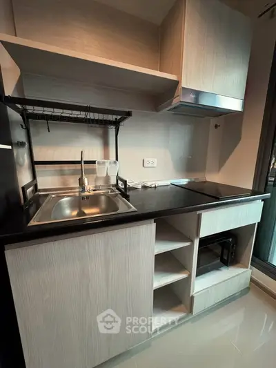 Modern compact kitchen with sleek cabinetry and built-in appliances in a stylish apartment.