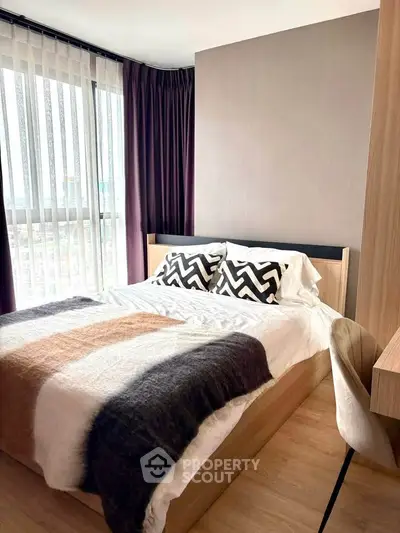Modern bedroom with stylish decor and large window offering natural light.