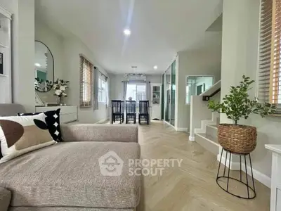 Spacious modern living room with elegant decor and dining area, featuring cozy seating and stylish wooden flooring.