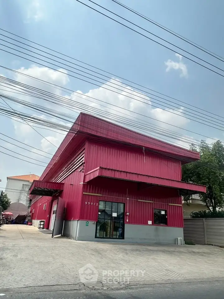 Modern red industrial building with spacious exterior and clear sky view.