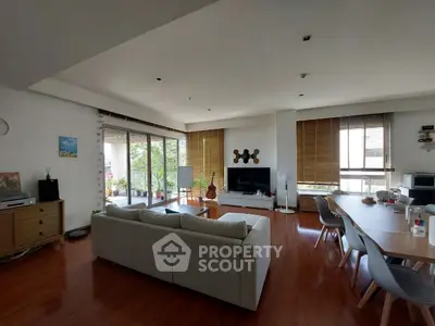 Spacious living room with modern decor and large windows opening to a balcony.