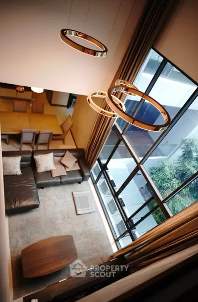 Stunning modern living room with high ceilings and large windows offering natural light and garden view.