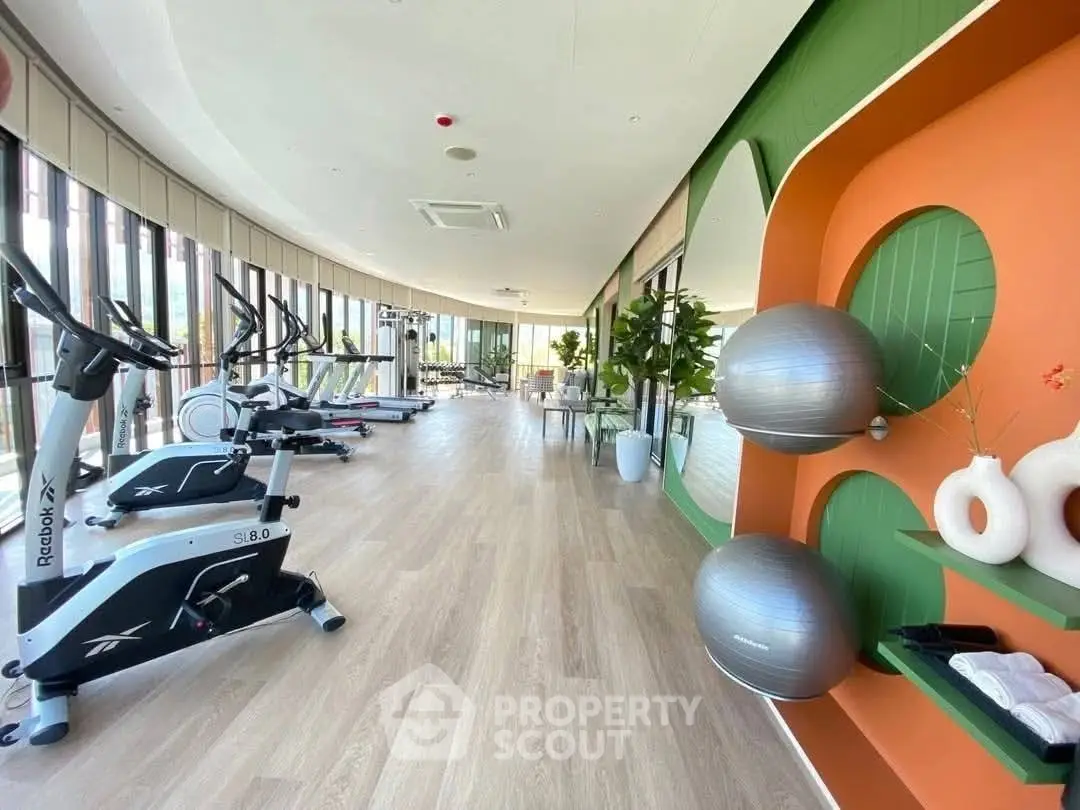 Modern gym with large windows and stylish decor in luxury residential building.