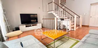 Spacious living room with modern staircase and large TV, perfect for family gatherings.