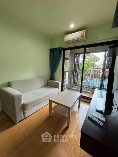 Cozy living room with balcony view, featuring a comfortable sofa and modern decor.