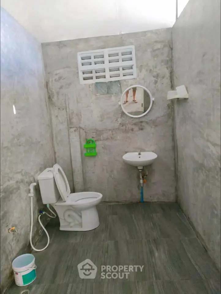 Minimalist concrete bathroom with modern fixtures and natural light.