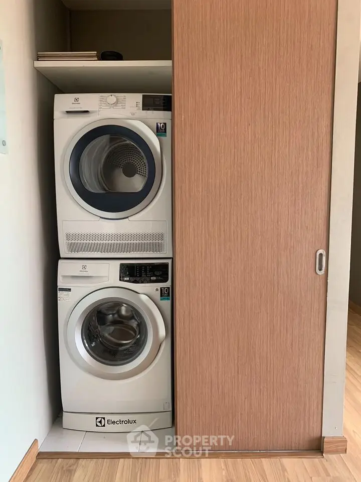Modern laundry area with stacked Electrolux washer and dryer in sleek wooden cabinet.