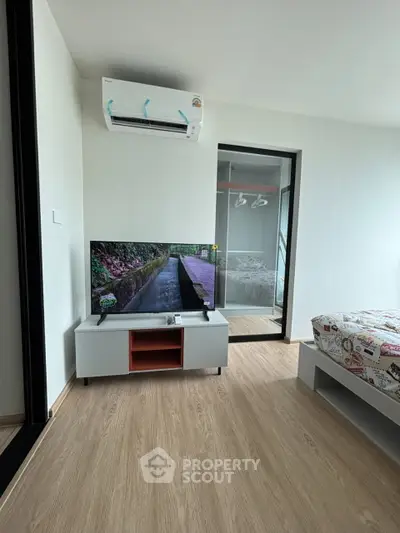 Modern bedroom with TV and air conditioning, featuring sleek design and natural light.