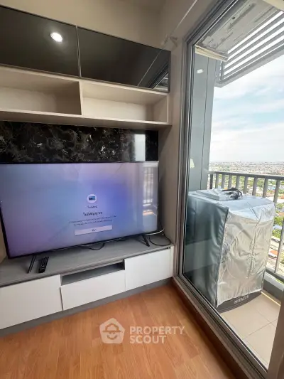 Modern living room with balcony view and sleek TV setup in a high-rise apartment.
