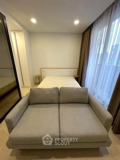 Cozy bedroom with modern sofa and natural light, perfect for relaxation and comfort.