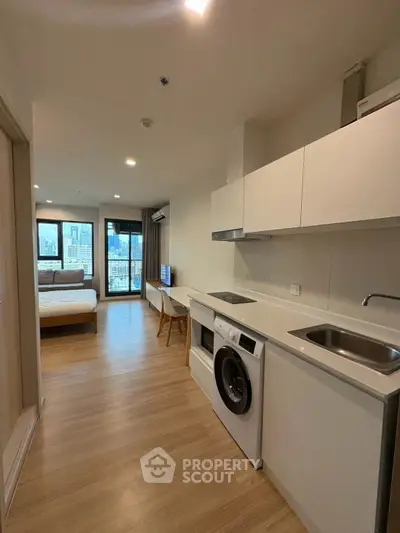 Modern apartment with open kitchen and city view, featuring washing machine and cozy bedroom.