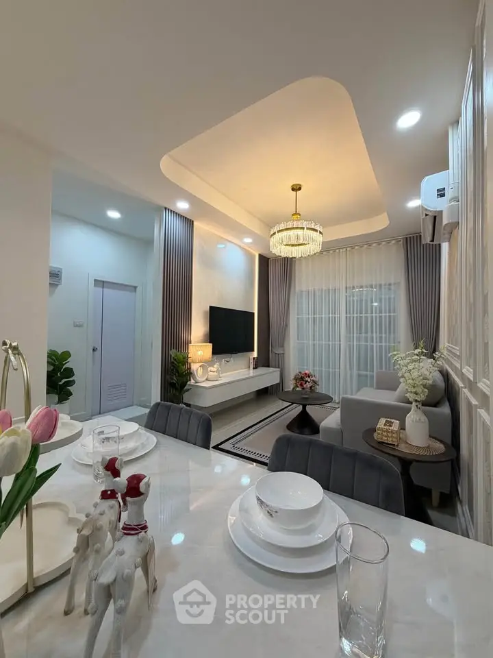 Elegant living room with modern decor, featuring a stylish chandelier and cozy seating area.