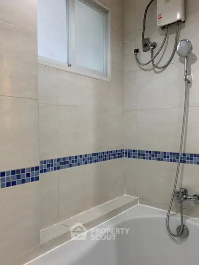 Modern bathroom with tiled walls and built-in bathtub featuring a showerhead and window.