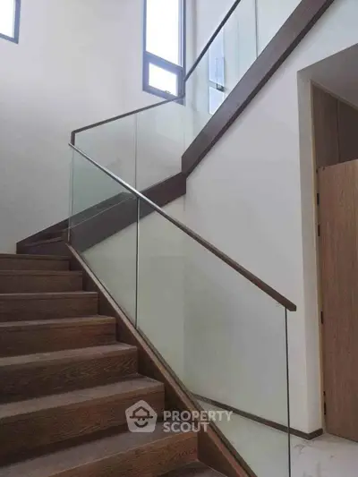 Elegant modern staircase with glass railing and wooden steps in a bright interior