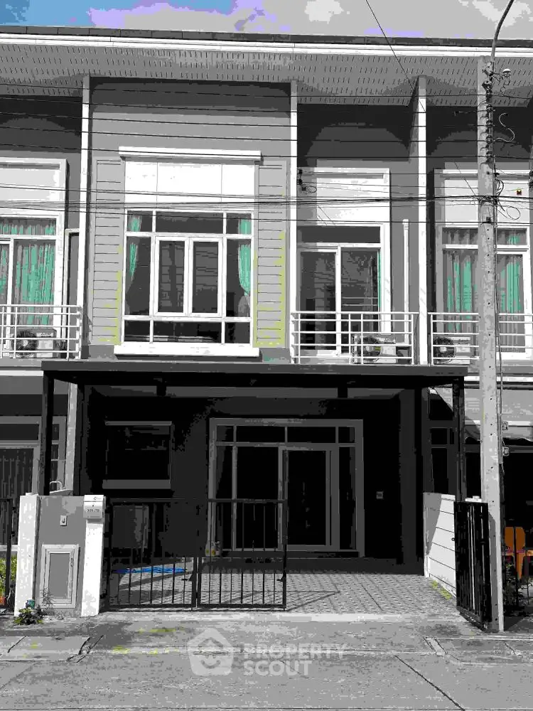 Modern townhouse exterior with large windows and gated entrance