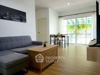 Spacious living room with modern decor and natural light, featuring a cozy sofa and dining area.