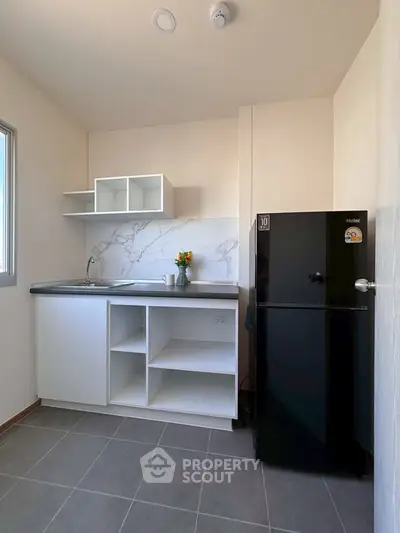 Modern minimalist kitchen with sleek black fridge and marble backsplash