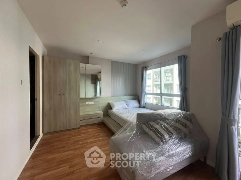 Spacious bedroom with modern furnishings and large windows in a stylish apartment.