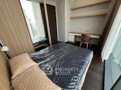 Modern bedroom with sleek design and city view, featuring a cozy bed and stylish workspace.