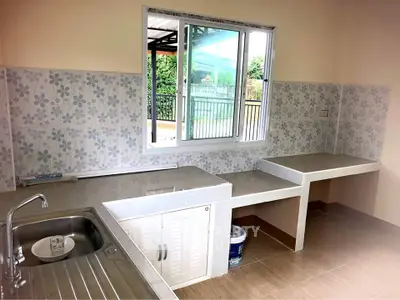 Charming kitchen with floral tiles and modern fixtures, overlooking a serene outdoor view.