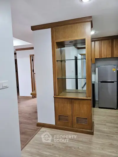 Modern kitchen with wooden cabinetry and stainless steel fridge in a cozy apartment.