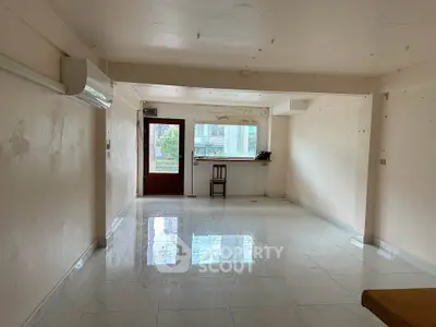 Spacious unfurnished room with glossy tiled floor and large window for natural light.