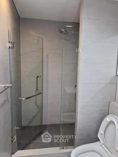 Modern bathroom with glass shower enclosure and sleek tile design.