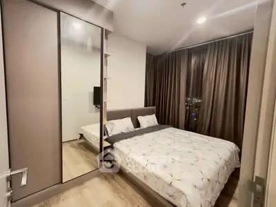 Modern bedroom with cozy double bed and mirrored wardrobe in stylish apartment.