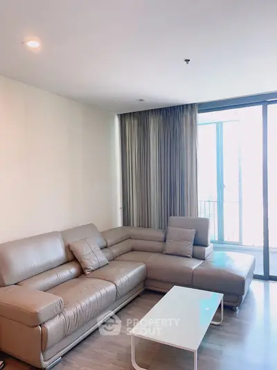 Spacious living room with modern leather sofa and large windows for natural light.