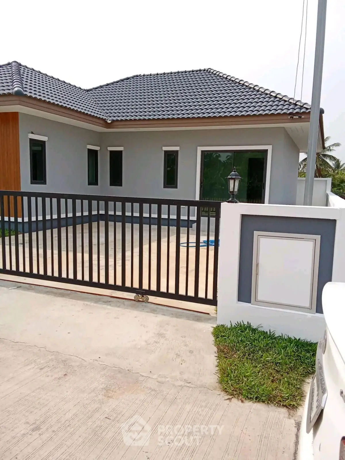 Modern single-story house with sleek design and gated entrance in serene neighborhood.