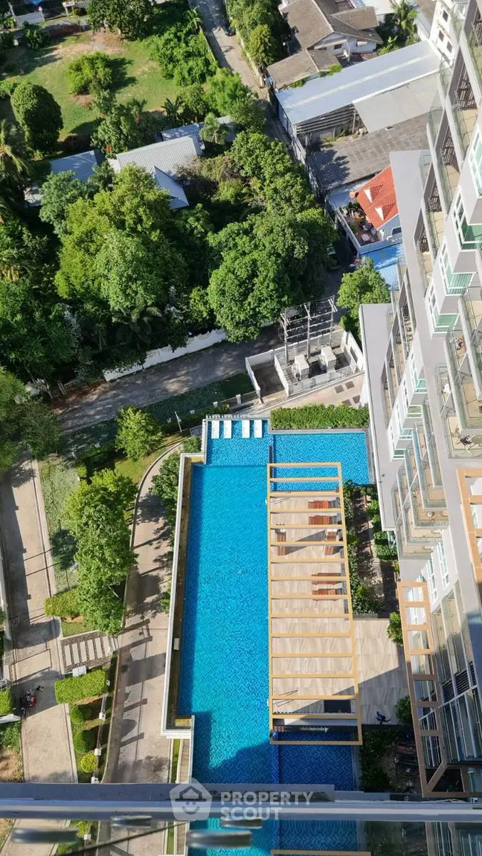 Stunning aerial view of modern apartment building with luxurious pool and lush greenery.