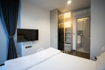 Modern bedroom with sleek design, featuring a wall-mounted TV and an ensuite bathroom.