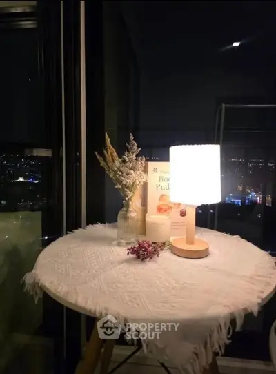 Cozy balcony with night view, featuring a small table with lamp and decor, perfect for relaxation.