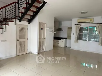 Spacious open-plan living area with modern staircase and kitchen in a bright, airy home.