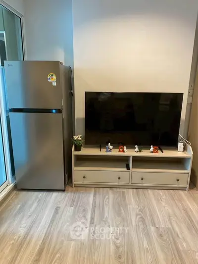 Modern living room with sleek TV setup and stainless steel fridge