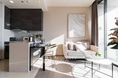 Modern open-layout living room with elegant kitchen and stylish decor, featuring natural light and cozy seating area.
