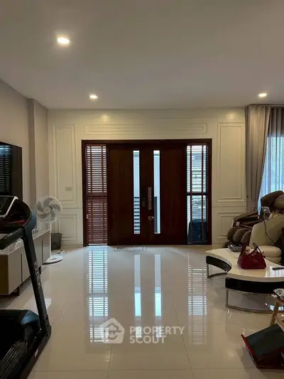 Spacious living room with modern decor and large wooden doors, perfect for relaxation and entertainment.