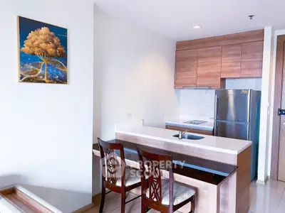Modern kitchen with sleek design, featuring a breakfast bar and stainless steel appliances.