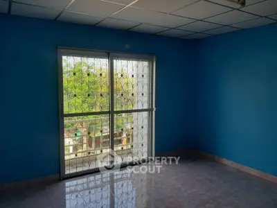 Spacious room with blue walls and large window offering natural light and garden view.