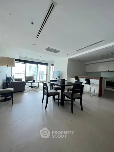 Spacious modern living room with open kitchen and city view.