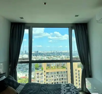 Stunning bedroom with panoramic city view through large window, featuring modern decor and cozy ambiance.