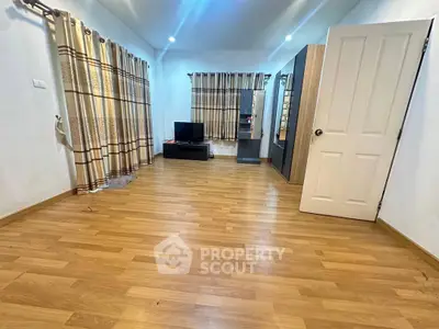 Spacious living room with wooden flooring and modern decor, perfect for relaxation and entertainment.