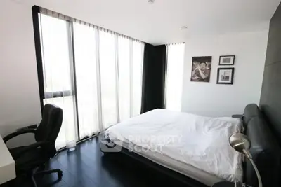 Modern bedroom with sleek black flooring and large windows for natural light.