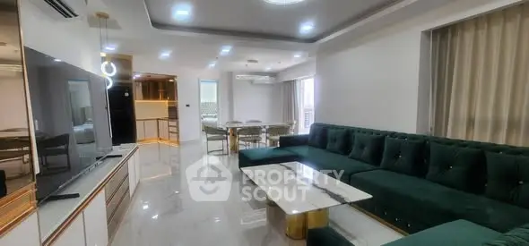 Luxurious modern living room with elegant green sofa and marble coffee table, open layout to dining area.
