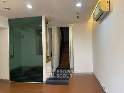 Spacious interior with modern glass partition and wooden staircase, ideal for office or retail space.