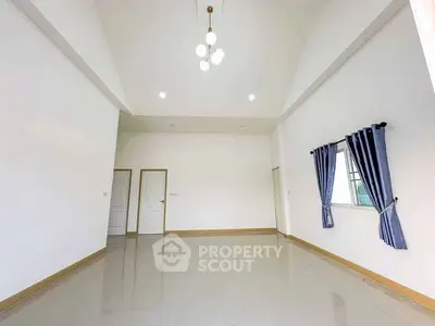 Spacious living room with high ceiling and modern lighting, featuring elegant curtains and polished flooring.