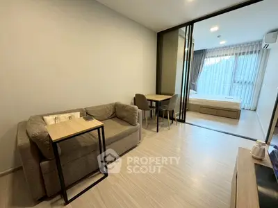 Modern studio apartment with cozy living area and bedroom separated by glass doors.